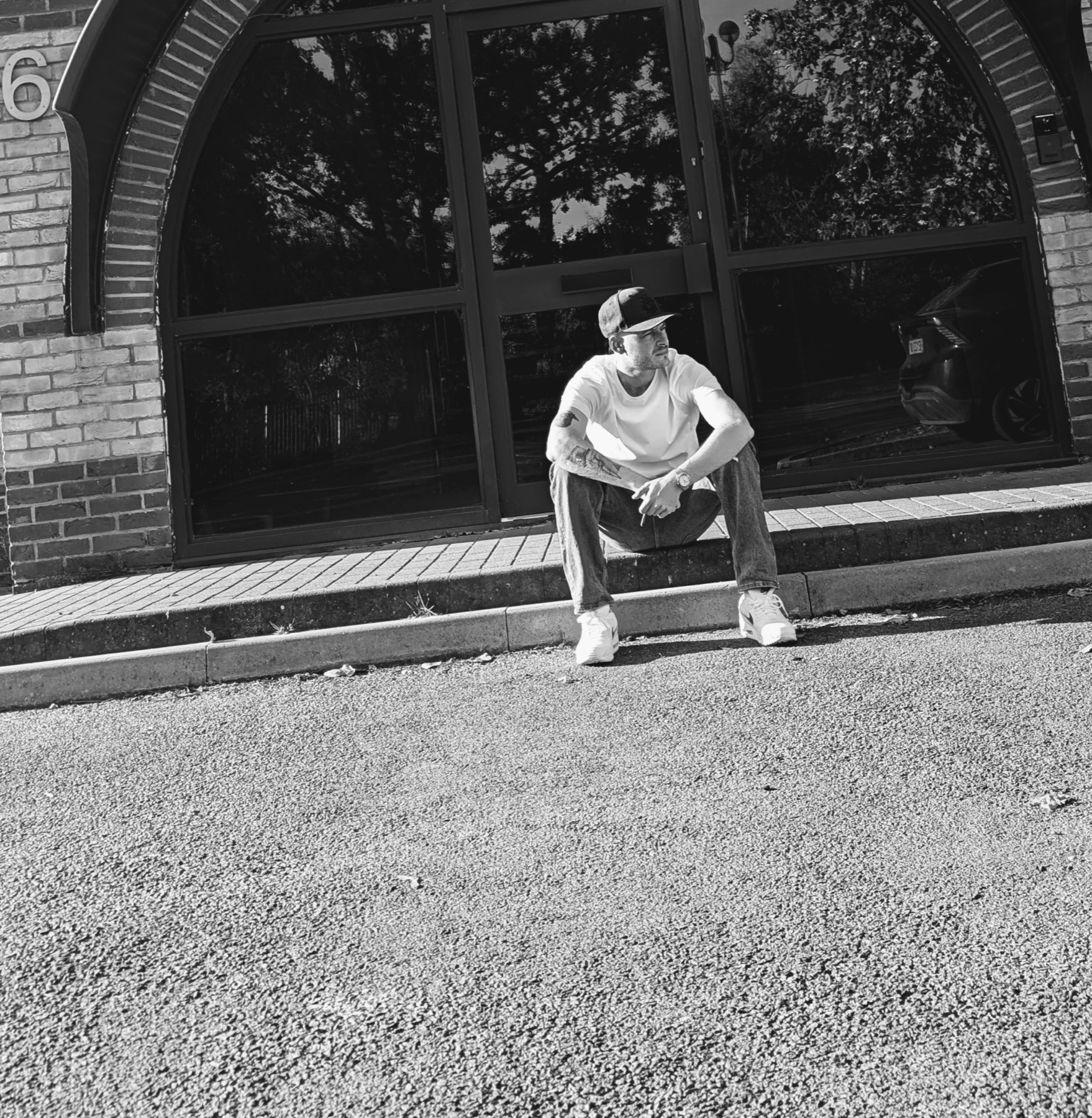 Black-and-white portrait of Telboy sitting outside a brick building