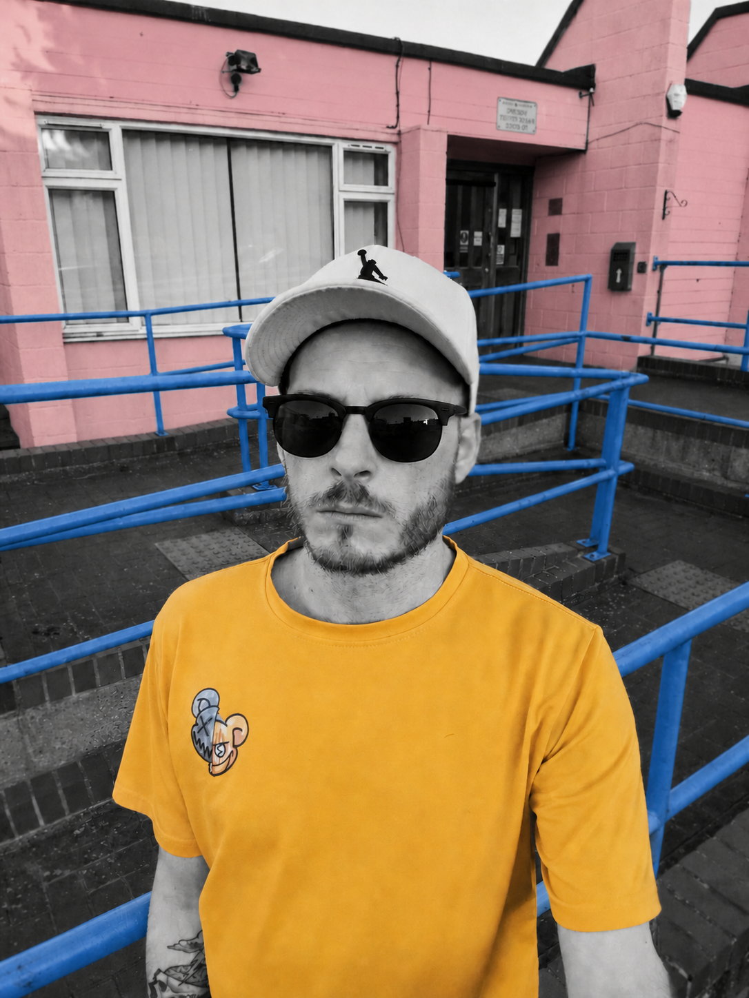 Telboy wearing sunglasses beside blue railings and a pink building